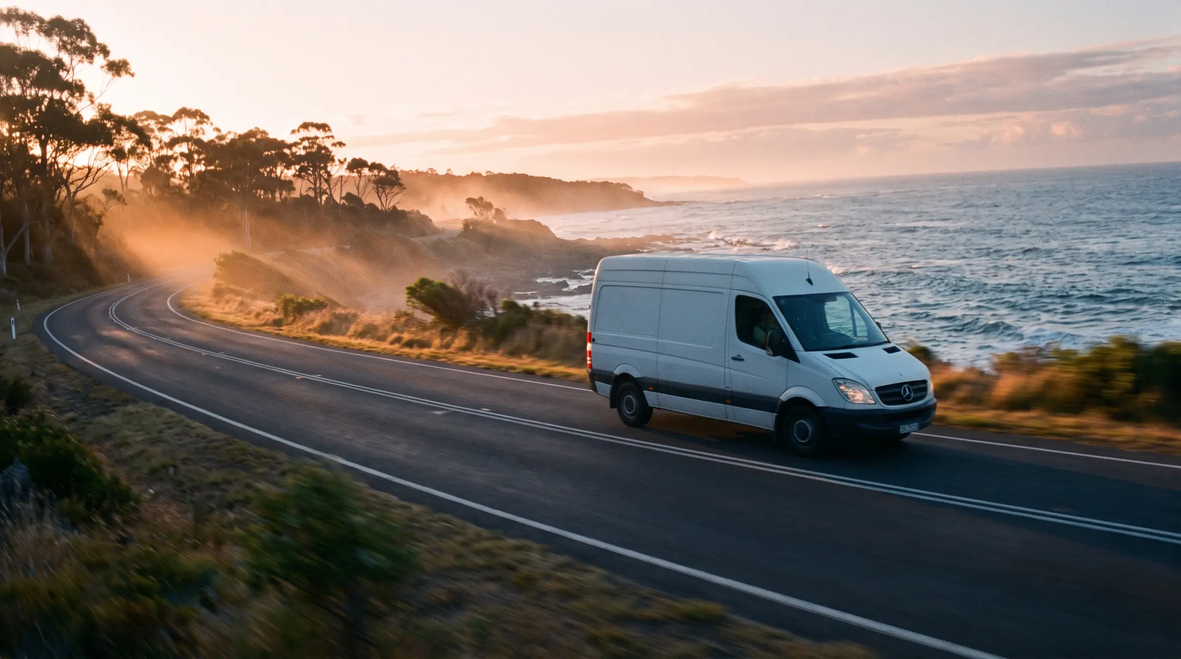 A delivery van on an Australian coastal road at sunrise